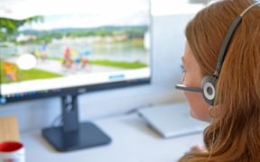 Mitarbeiterin mit Headset vor Computer