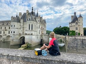 Cyclist takes a break in front of a beautiful French castle backdrop