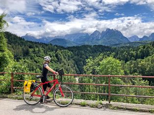 Radlerin auf dem Alpe-Adria-Radweg mit Ausblick auf Berge