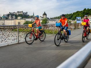 Radfahrer am Makartsteg mit Salzburger Altstadt im Hintergrund