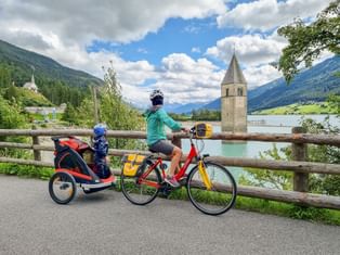 Cycling family marvelling at the sunken church tower of Lake Reschen