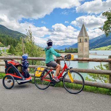 Cycling family marvelling at the sunken church tower of Lake Reschen